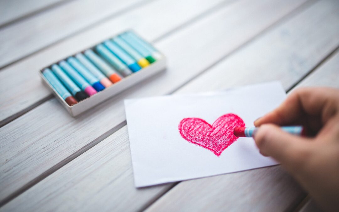 Crayons with paper with a red heart drawn on it