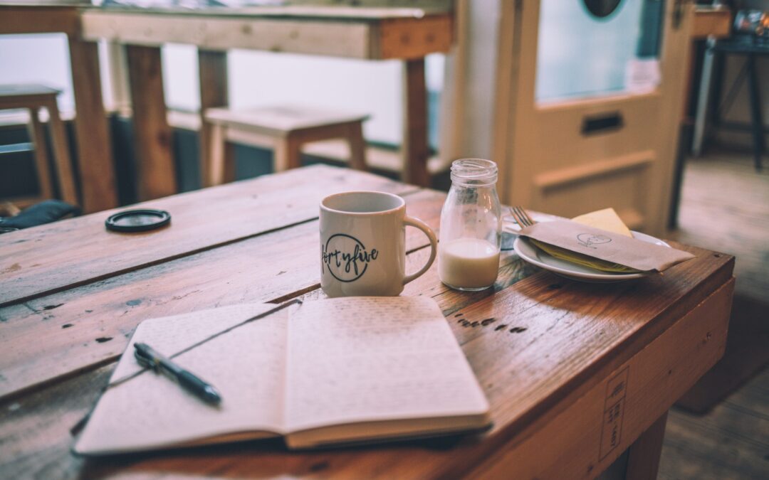 a wooden table has a book and a mug and some milk on it.