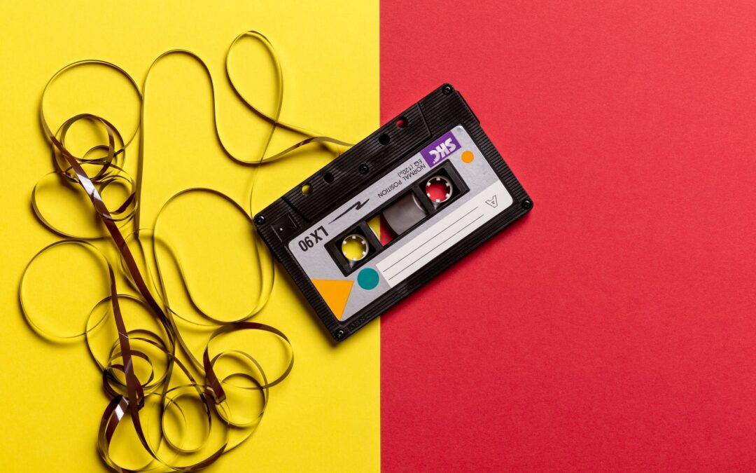 a cassette tape sits with its tape spooled out in ribbons against yellow and red paper