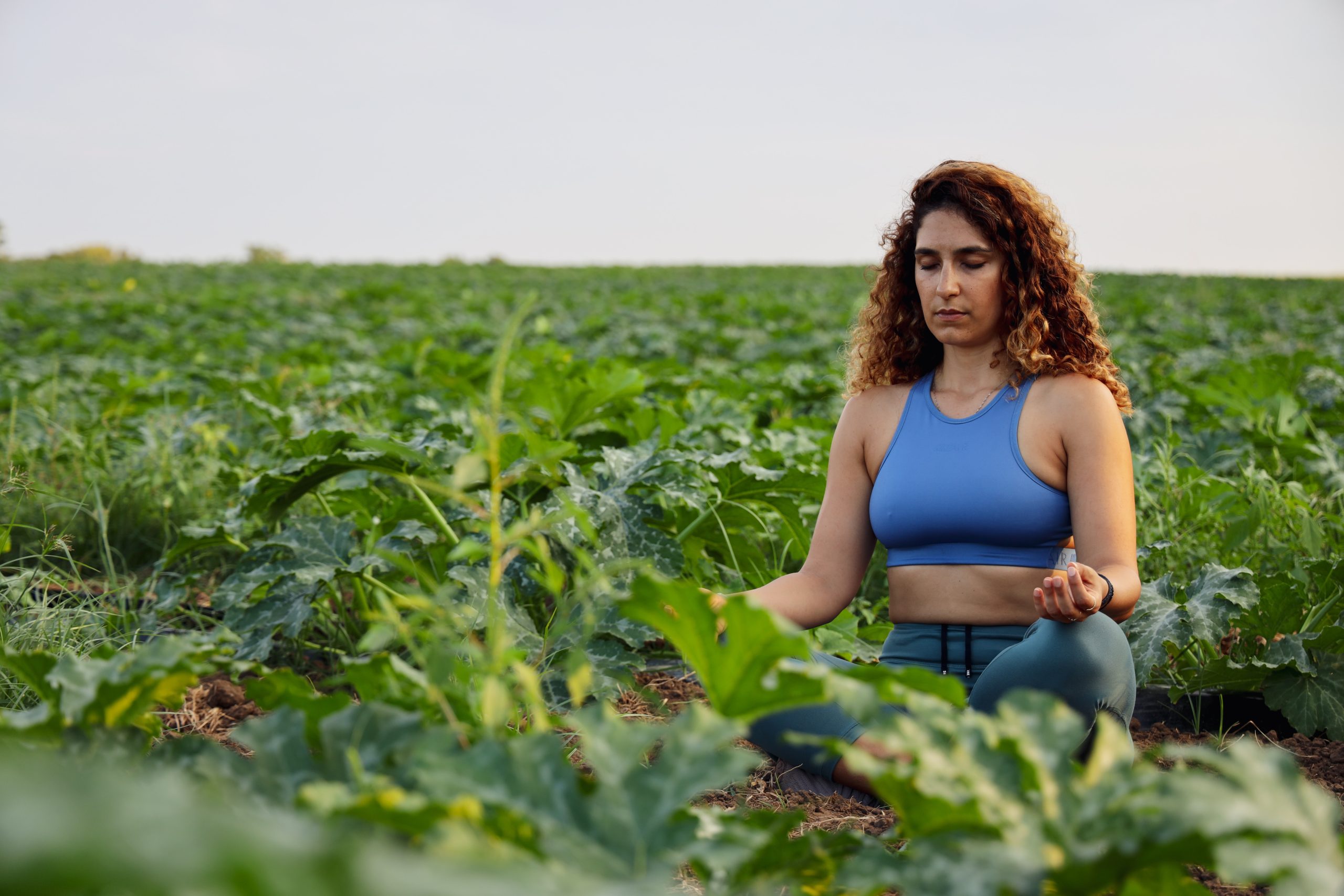 Woman meditating in lush, green field