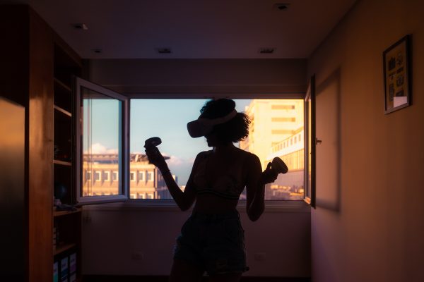 dark silhouette of a person with a virtual reality headset standing in a dark room