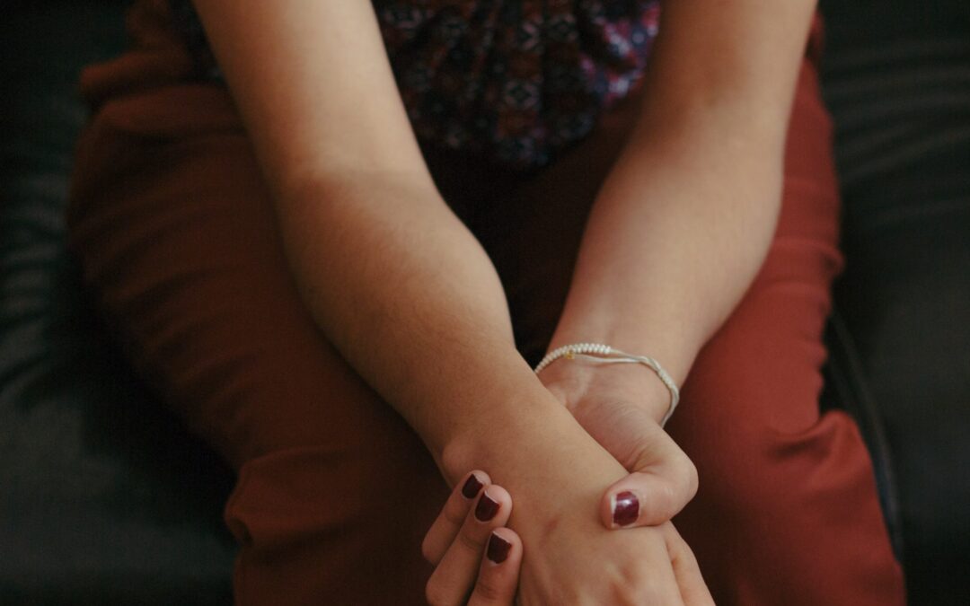 Depression Symptoms - a person sitting with her hands folded in her lap