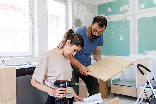 Father and his daughter with hearing aid installing furniture together.