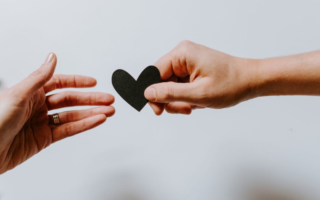 Two people holding a black heart, supporting one another, similarly to what do peer support specialists do.