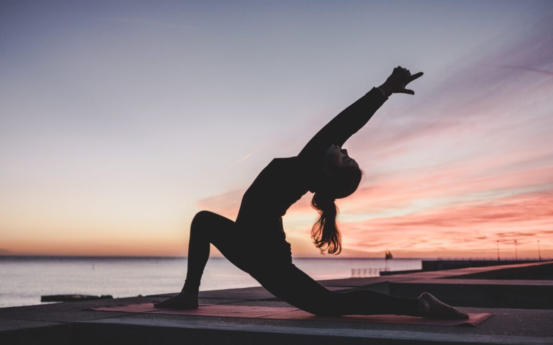 A woman doing yoga at nite in the open against a harbor