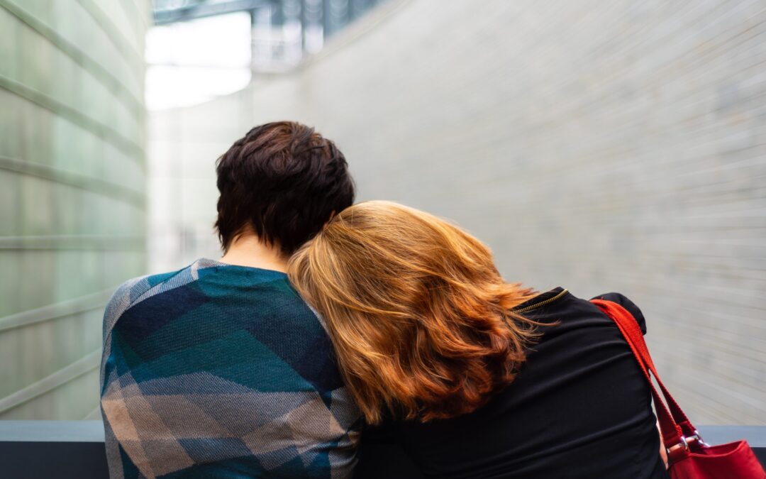 a woman with red hair is leaning her head on another person, both people are standing on a balcony.