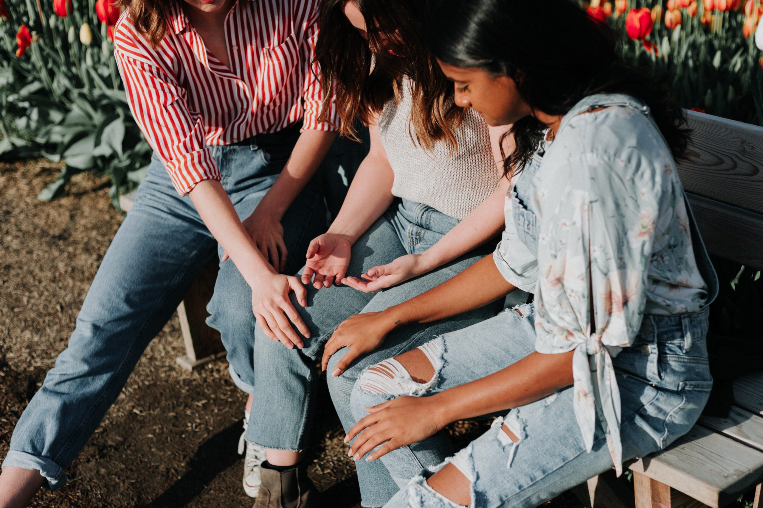 3 women ar sitting together looking at the middle womans upturned hands on her lap.