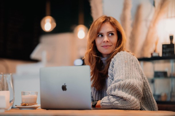 Unusual Locations a woman is at a cafe with her laptop and a glass of milk.