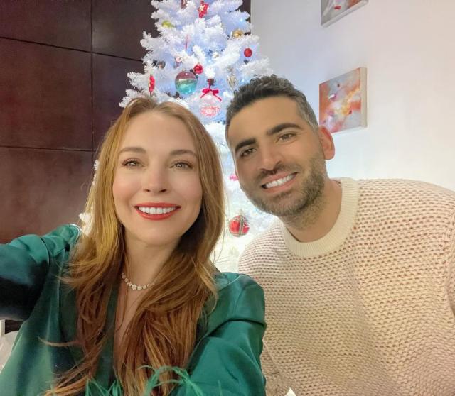 A man and woman are in front of a white xmas tree looking at something