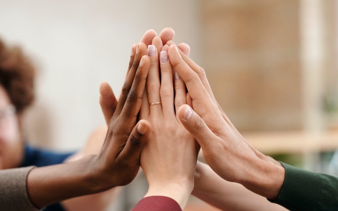 People are joining their hands as a sign of support, showing the important role of peer support for families affected by addiction.