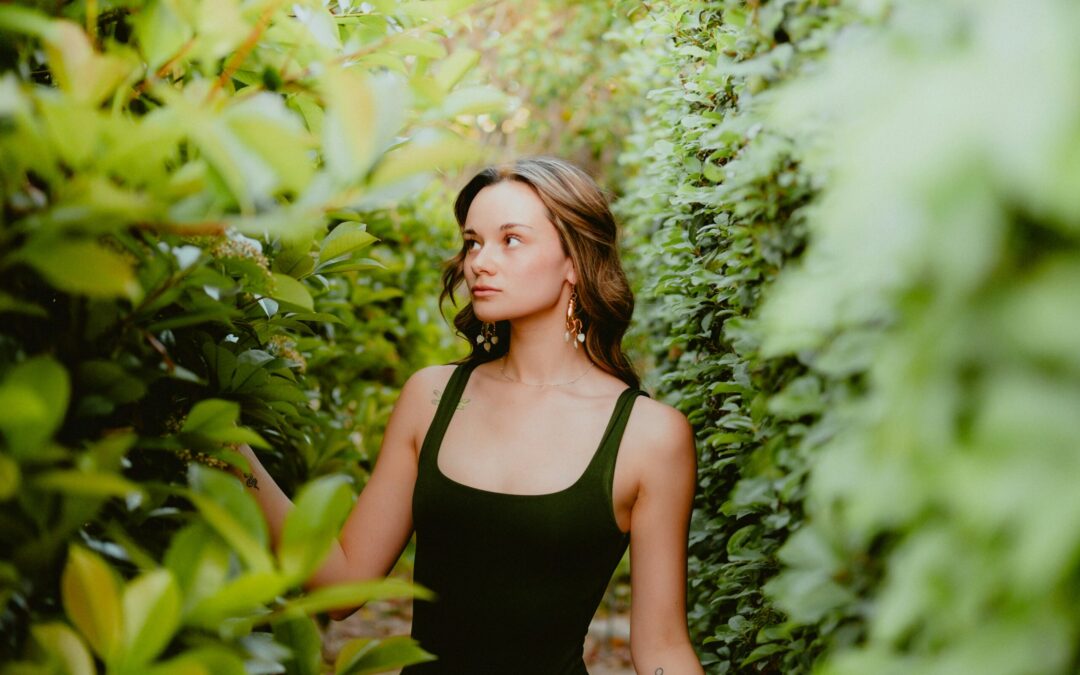 a woman in a black dress standing in front of a bush